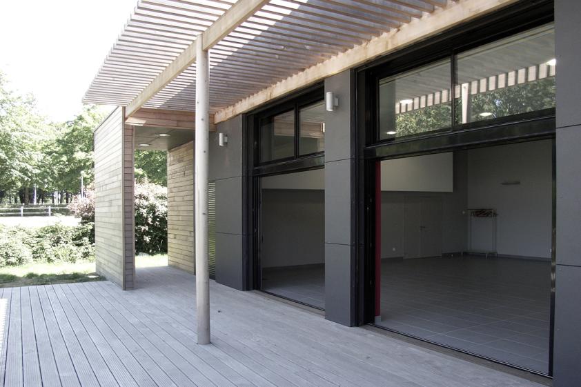Terrasse extérieure abritée avec vue panoramique sur les terrains de sports.