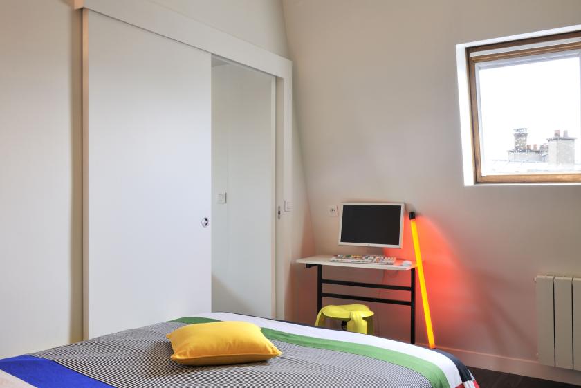 Chambre à coucher sous les combles, porte coulissante en applique.