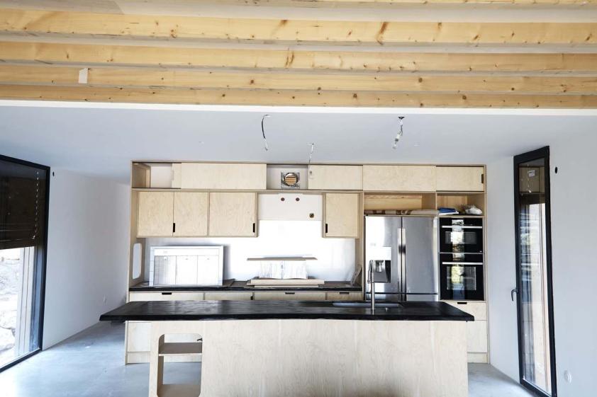 Cuisine sur mesure en CP et bois brûlé, depuis le salon