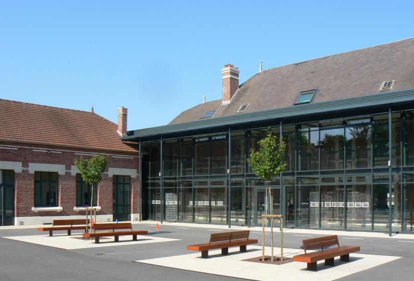 Photographie diurne de la galerie de distribution vitrée depuis la cour de récré