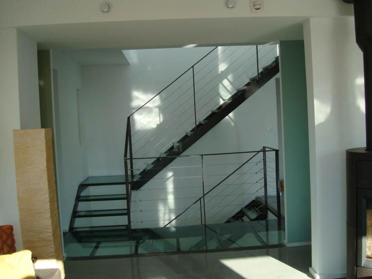 Vue sur l'escalier en verre, puit de lumière, colonne vertébral de la maison des