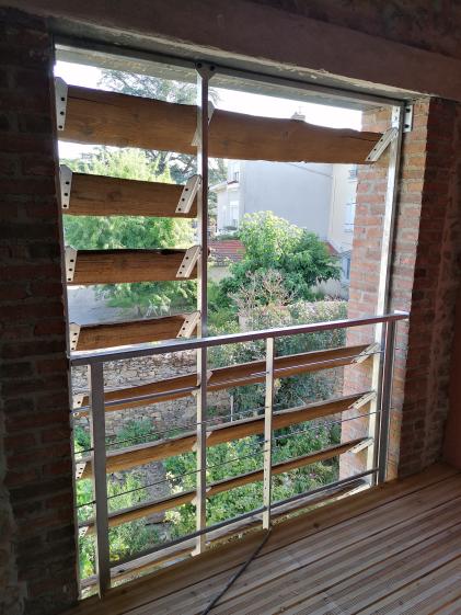 Vue sur l'extérieur à travers un brise vue en bois du site récupéré