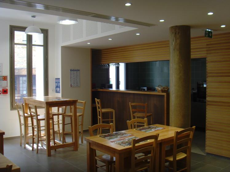 La salle du bistrot avec en arrière plan, le bar et la cuisine ouverte.