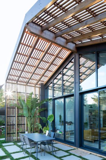 Une pergola en bois protège le mur rideau et la terrasse du soleil.
