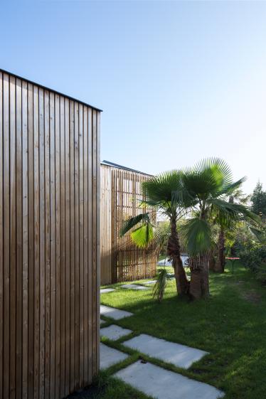 La bardage bois s'insère dans le jardin et s'ajoure pour créer la pergola.