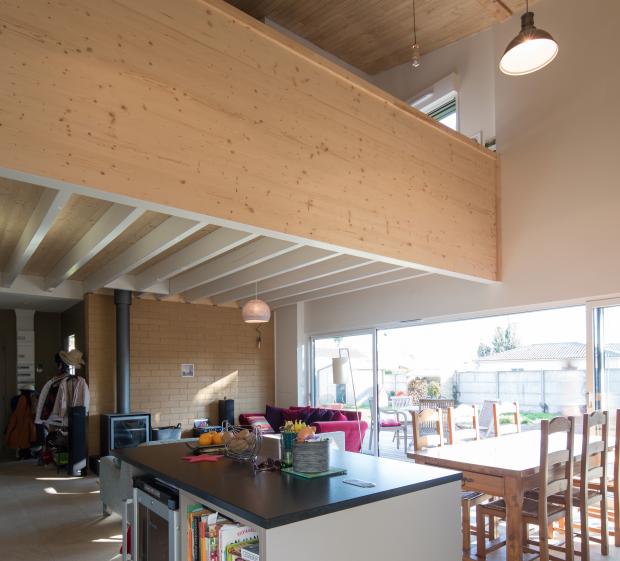 La mezzanine de l'étage s'ouvre sur la double-hauteur, le poêle s'adosse au mur 