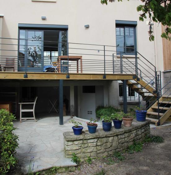 La terrasse est réalisée en ossature bois, poteaux et garde-corps en acier laqué