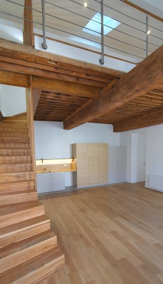 Vue depuis l'entrée, l'escalier d'accès à l'étage et la cuisine en fond de pièce