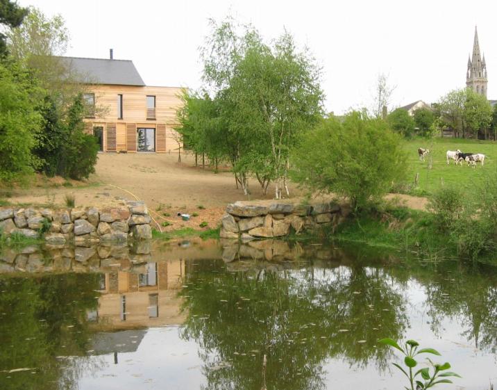 Vue de l'étang : La maison et le bourg, le clocher en point de repère des pièces