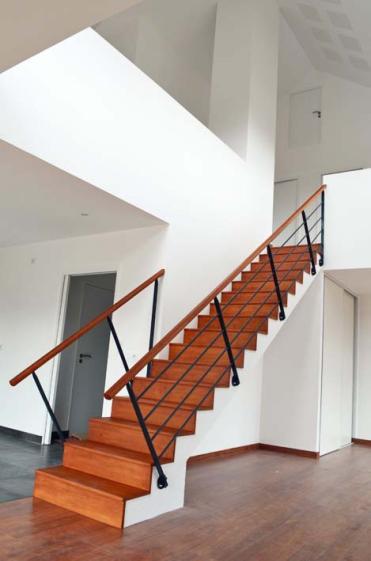 Dans l'atrium, l'escalier droit de béton habillé de bois mène à l'étage.