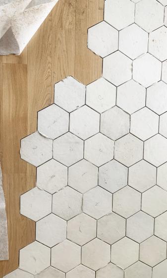 Pose du carrelage hexagonal en chantier, découpe avec le parquet chêne du séjour