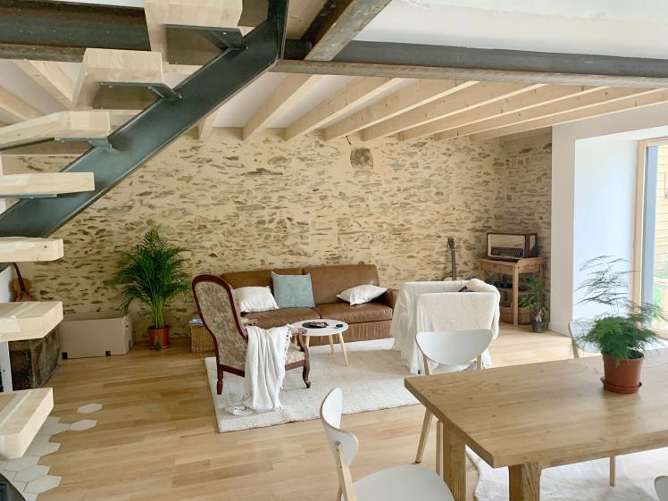 Vue du séjour sur le salon, avec l'ambiance chaleureuse apportée par le mur en p