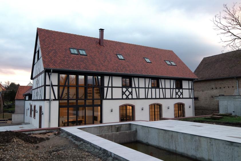 Reconstruction d'un corps de ferme alsacien, façade sud moderne avec baie monumentale donnant sur la piscine