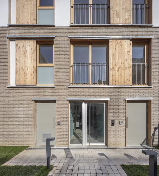Boulogne // Entrée de l’immeuble, le socle en brique pleine assure la solidité et l'enduit à la chaux dialogue avec la pierre calcaire. Cadres et volets en bois marquent la transition entre rue et intimité intérieure.