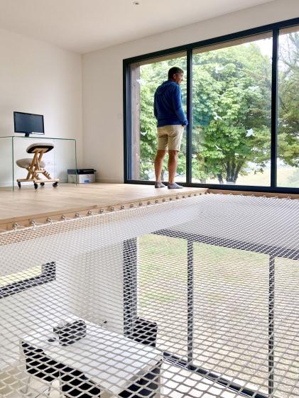 Transformation d'un hangar en maison : vue de la mezzanine avec son flet pour la sieste