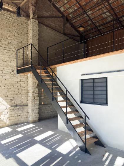 Transformation d'un hangar en maison : vue de l'escalier vers la terrasse supérieure