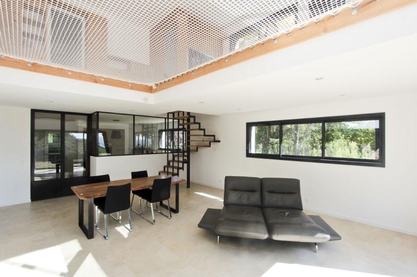 Transformation d'un hangar en maison : vue de la pièce de vie et verrière de la cuisine au fond