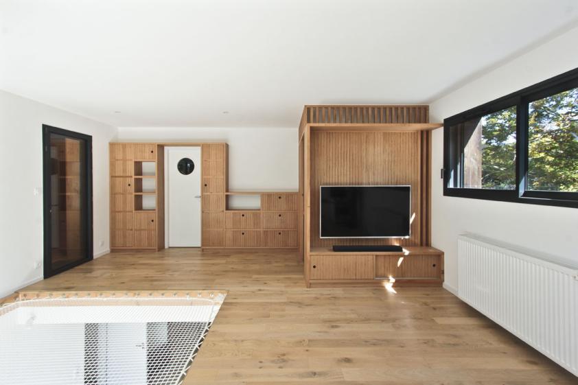Transformation d'un hangar en maison : vue de la mezzanine avec son flet pour la sieste et mobilier sur mesures