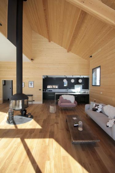 Construction d'un châlet contemporain dans les pyrénées par l'atelier S architecte à Toulouse  : intérieur avec poêle suspendu Focus et la cuisine au fond