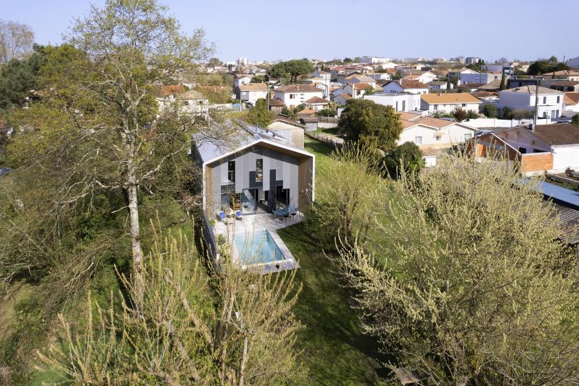 Vue semi-aérienne de la maison. Celle-ci est entourée d'arbres de hautes futaies. 