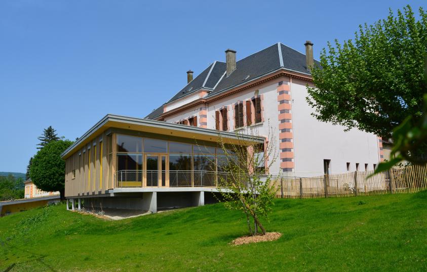 Le restaurant scolaire, en extension de l'école. Porte-à-faux, façade-rideau, bardage prégrisé.