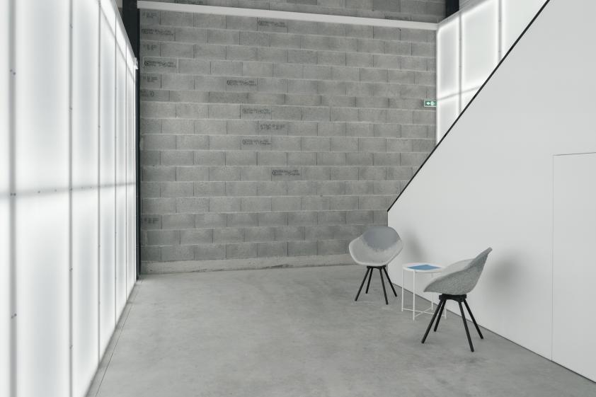 Bureau aux murs légers en polycarbonate translucide, éclairé par des néons diffusant une lumière douce et homogène.