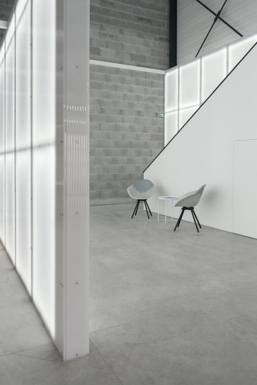 Bureau aux murs légers en polycarbonate translucide, éclairé par des néons diffusant une lumière douce et homogène.