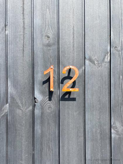 Détail numéro bardage bois noir, numéro en acier oxydé