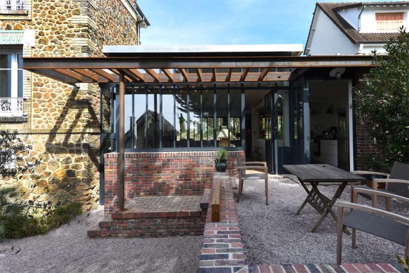 Vue de la façade en brique, des menuiseries en acier et de la pergola