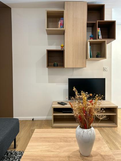 Meuble TV en bois avec étagères murales asymétriques intégrées, optimisant le rangement dans un séjour de colocation