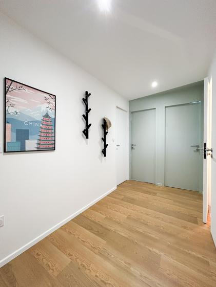 Couloir lumineux avec parquet bois, portes de chambres et patères murales, facilitant la circulation dans un appartement en colocation