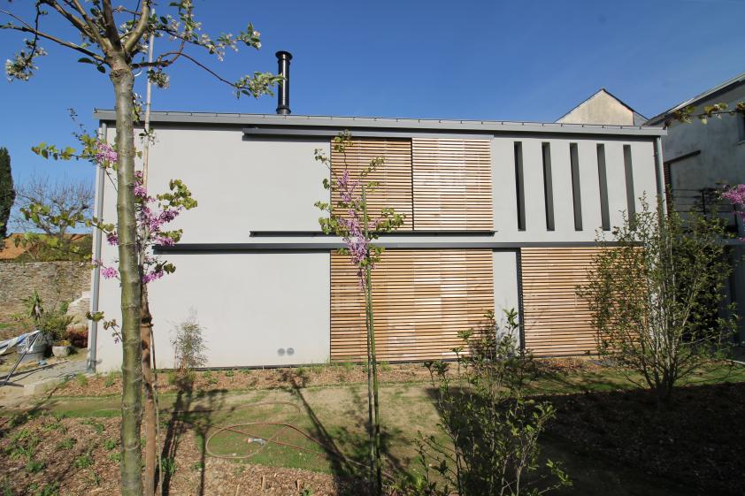 Le bâtiment fermé par des volets bois coulissants le protège du soleil sans occulter les vues depuis l'intérieur.
