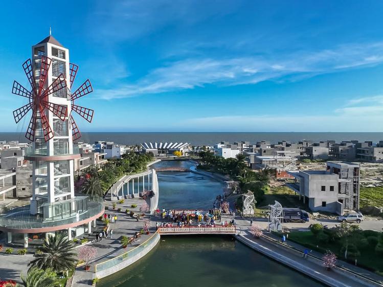 Tour belvédère panoramique rappelant un moulin rouge, située au centre de The Maris Vung Tau, avec café au rez-de-chaussée, la terrasse adjacente en forme de proue de bateau et pont adjacent