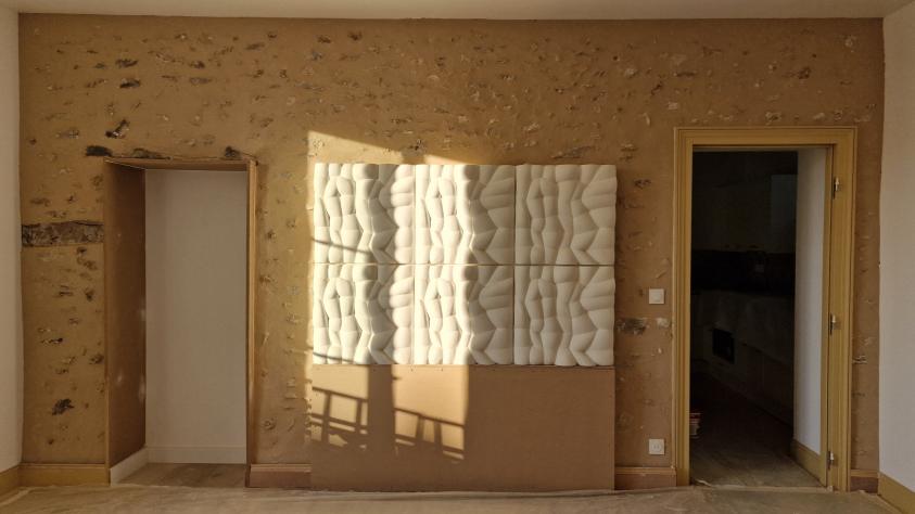 Détail de mur laissé brut avec tête de lit en nuage