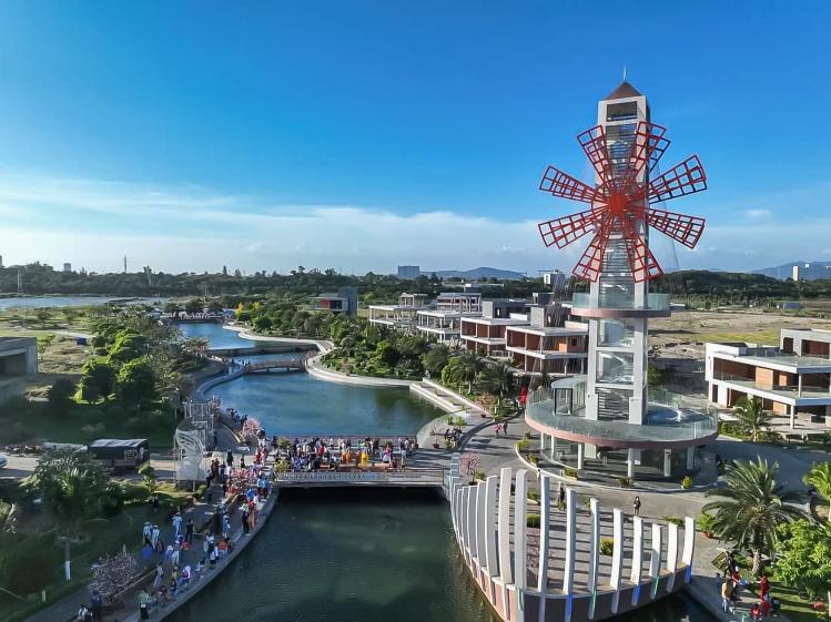 Tour belvédère panoramique rappelant un moulin rouge, située au centre de The Maris Vung Tau, avec café au rez-de-chaussée, la terrasse adjacente en forme de proue de bateau et pont adjacent.