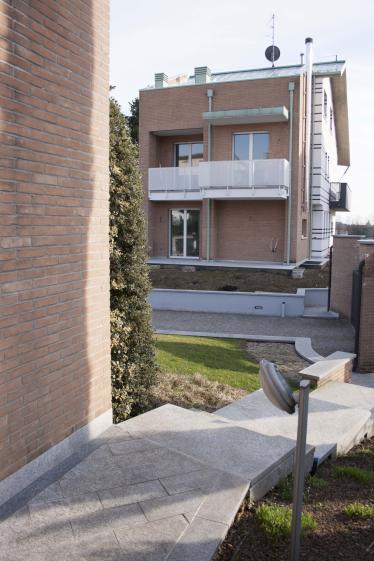 Vue jardin – espace extérieur privatif et traitement des abords Vue sur jardin d'une maison jumelée contemporaine à Bellusco, Italie — parement brique, balcons et aménagement extérieur en granit