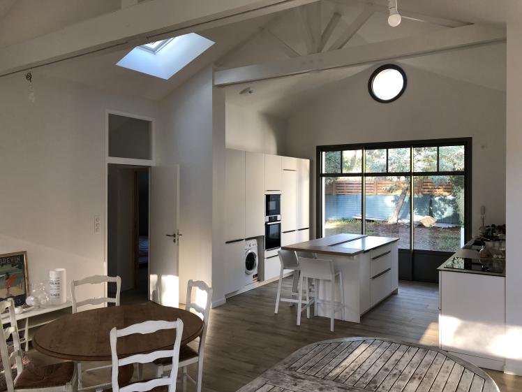 Vue intérieure vers la cuisine, hublot et puits de lumière en toiture, belle hauteur sous toiture