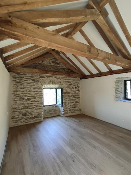 Charpente en châtaignier Charpente traditionnelle en bois de châtaignier, taillée à la main, révélée dans un espace épuré et lumineux.
