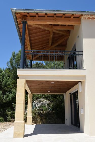 Création d’une terrasse couverte intégrant une structure en pierre et une charpente apparente, en lien avec les volumes de la maison.