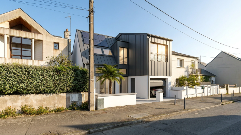 La Maison contemporaine à Rennes issue de la transformation et de la surélévation d’une habitation existante, mêlant volumes épurés, bardage métallique anthracite et grandes ouvertures lumineuses dans une écriture architecturale bioclimatique.