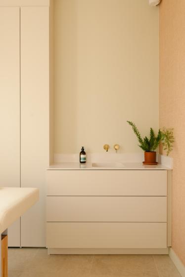 Cabine de soin du spa BEROA à Arcachon avec mobilier sur mesure blanc, robinetterie dorée, revêtement mural texturé et ambiance douce inspirée du bien-être.