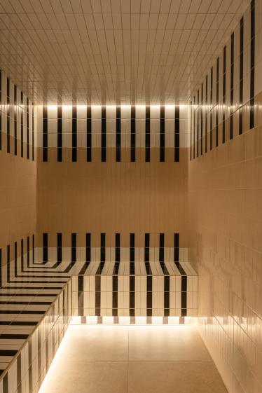 Hammam de luxe conçu par Eraiki.studio à Arcachon, avec revêtement en carreaux noir et blanc, lignes graphiques inspirées de l’Art déco et éclairage d’ambiance chaleureux.