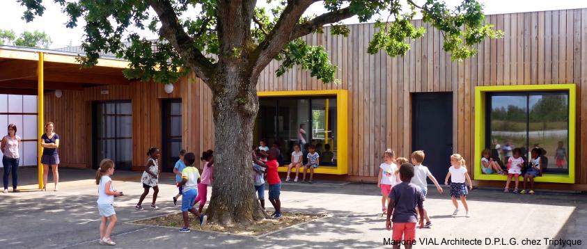 Une des cours du centre de loisir : Construction contemporaine à ossature bois avec de grands cadres de fenêtre colorés et débordants servant de bancs pour les enfants.