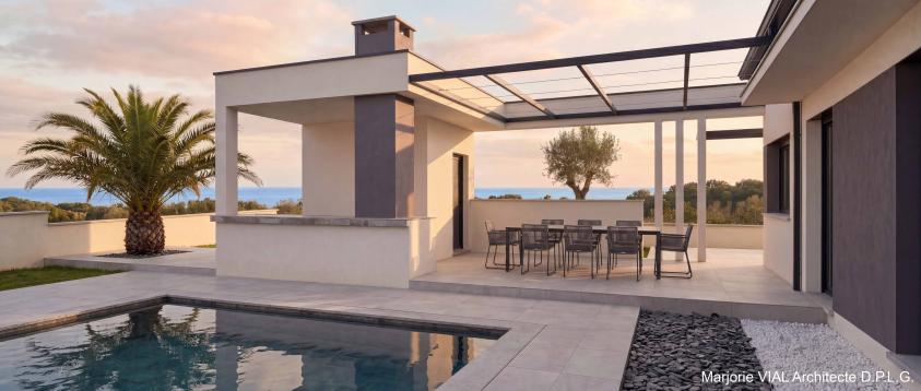 Maison contemporaine haut de gamme d'une surface plancher de 160 m². Volumes épurés en maçonnerie blanche et grise, casquettes et claustras béton, pergola épurée en profils métalliques et câbles noirs.