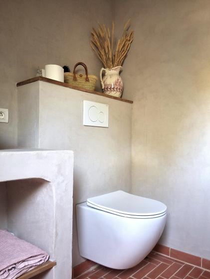 Salle de bain avec enduit à la chaux effet béton ciré, tablettes chêne, tomettes au sol