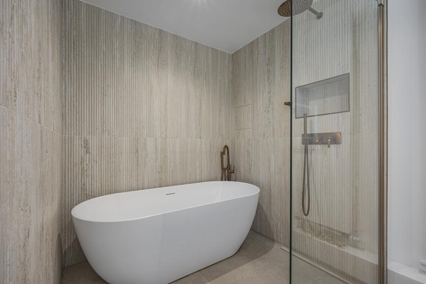 Vue rapprochée de la baignoire et de son aménagement dans la salle de bain parentale d’un appartement haussmannien rénové.