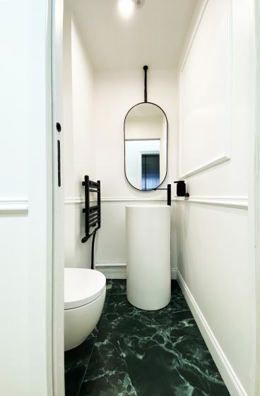 WC invités – Marbre vert et détails sur mesure WC invités rénovés dans un appartement haussmannien, avec revêtement de sol en marbre vert, vasque et miroir.