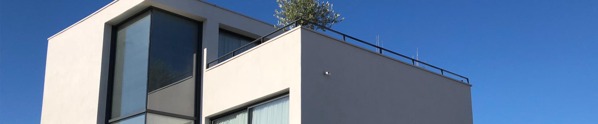Photo d'un bâtiment contemporain blanc avec une grande baie vitrée sur ciel bleu