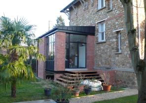 vue de l'extension et de la terrasse bois avec l'escalier permettant l'accès au 