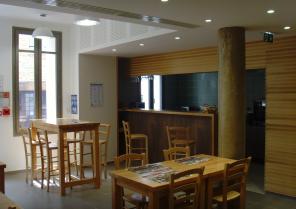 La salle du bistrot avec en arrière plan, le bar et la cuisine ouverte.